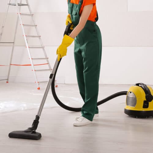 Addetta alle pulizie che pulisce il pavimento di un ufficio appena ristrutturato con un'aspirapolvere 