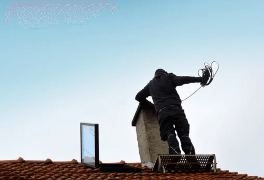 Uno spazzacamino con le adeguate protezioni che lavora sul tetto di una casa